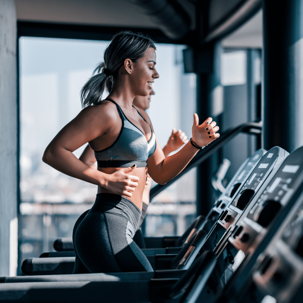 A woman in athletic wear running on a treadmill in a modern, well-lit gym.